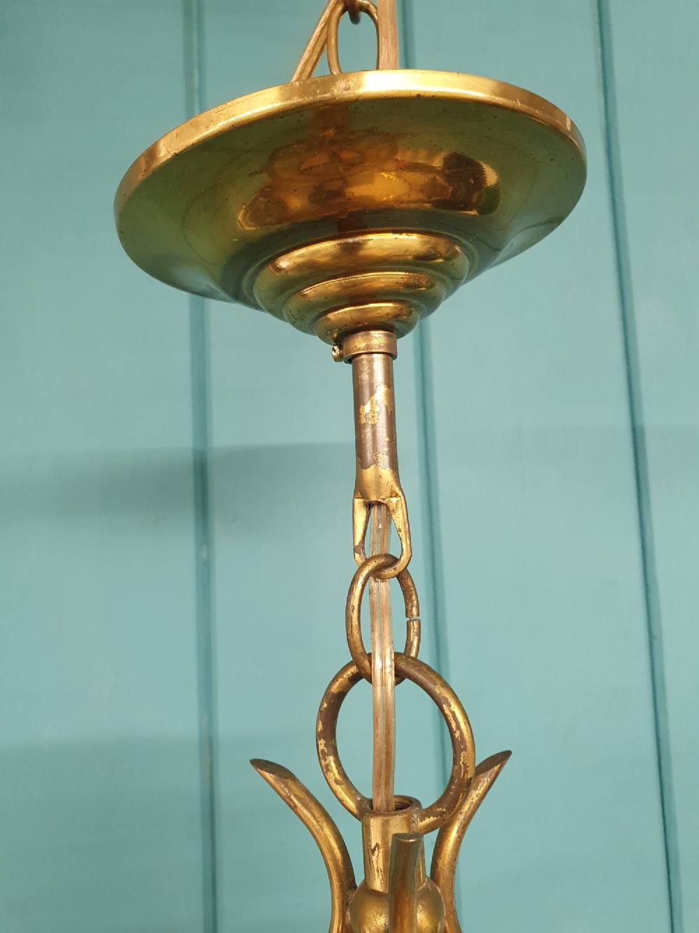 An early 20th-century brass hall lantern with a cylindrical glass shade, internal light fitting, arched crown top, and suspension chain. View V