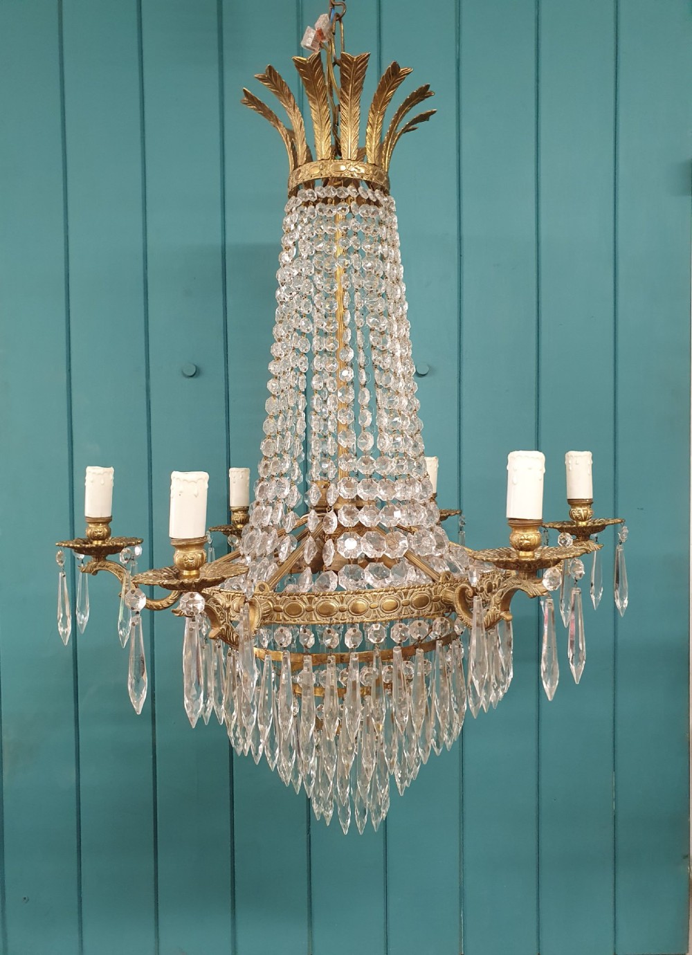 A six-arm brass tent chandelier decorated with crystal beads, drop pendants, and a leaf corona at the top.