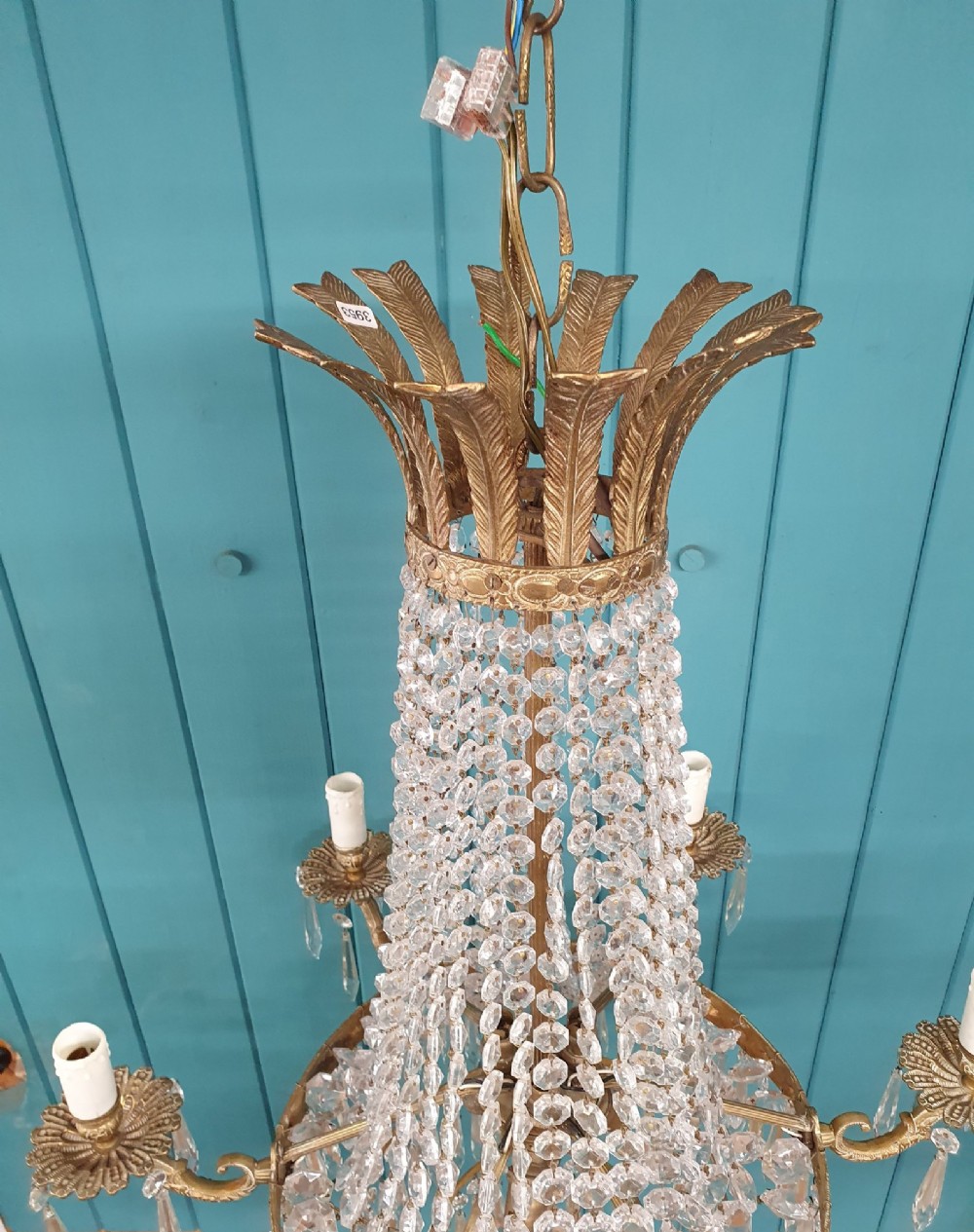 A six-arm brass tent chandelier decorated with crystal beads, drop pendants, and a leaf corona at the top. View II