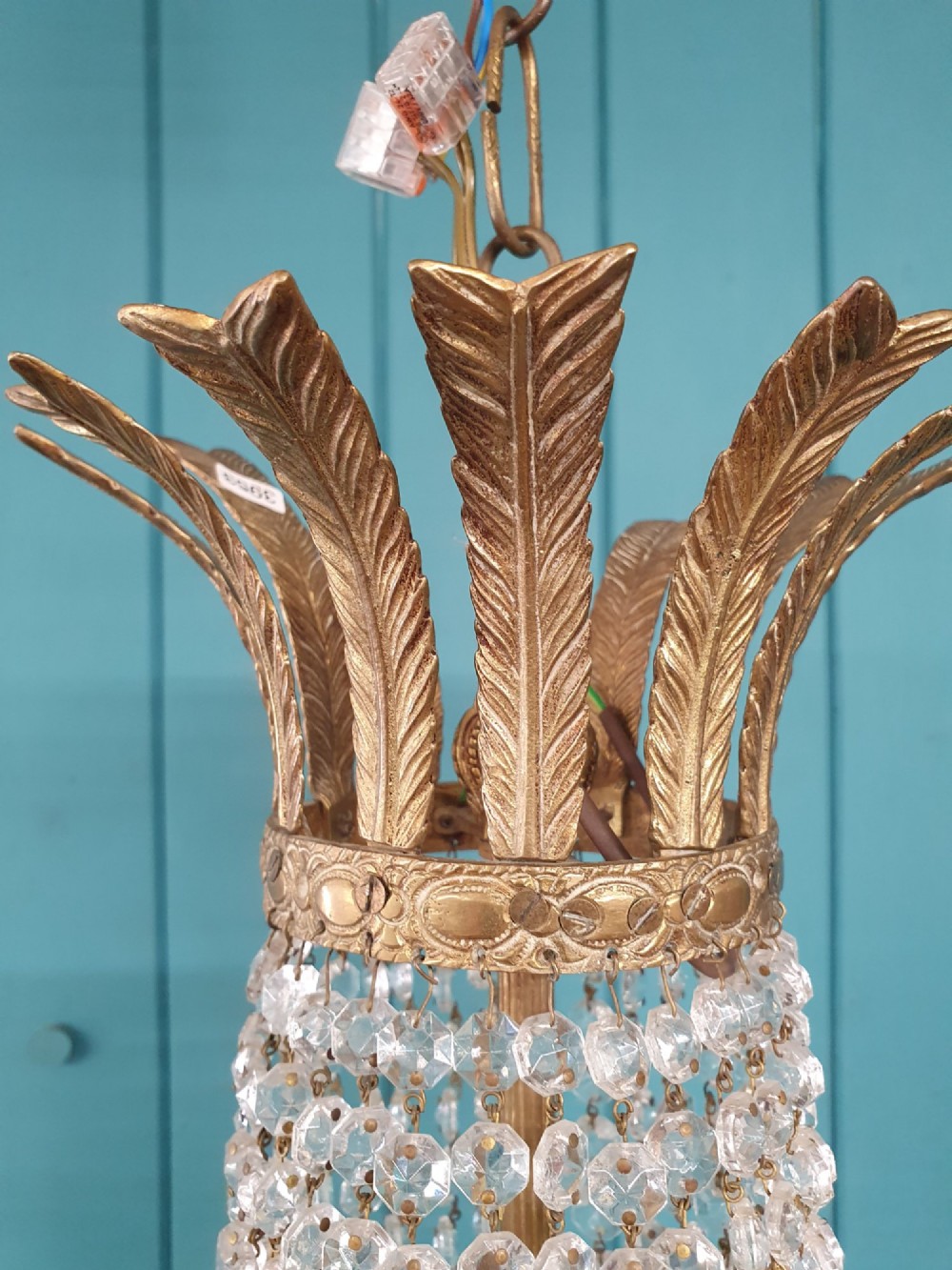 A six-arm brass tent chandelier decorated with crystal beads, drop pendants, and a leaf corona at the top. View VIII