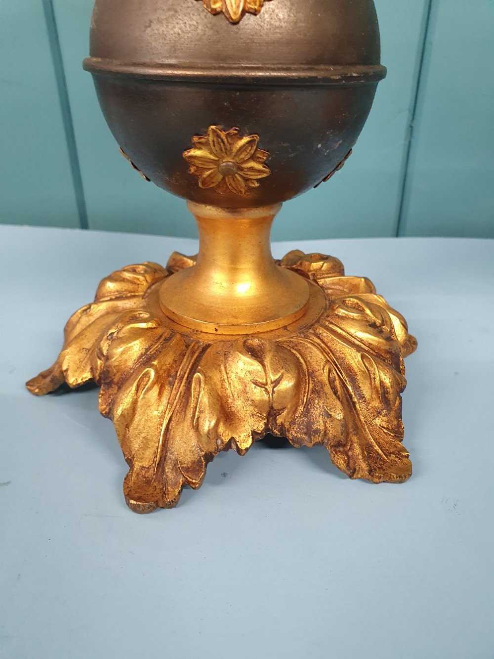 A pair of early 20th-century gilt brass table lamps featuring flared acanthus leaf bases, dark spherical central sections with gold floral mounts, and turned upper columns. View III