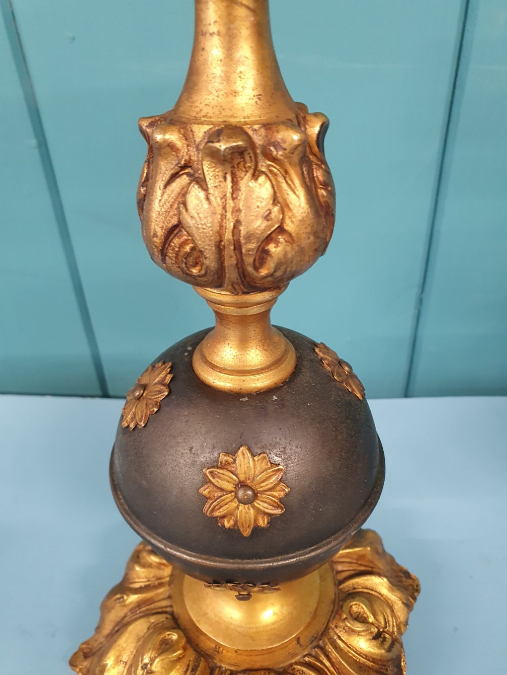 A pair of early 20th-century gilt brass table lamps featuring flared acanthus leaf bases, dark spherical central sections with gold floral mounts, and turned upper columns. View IV