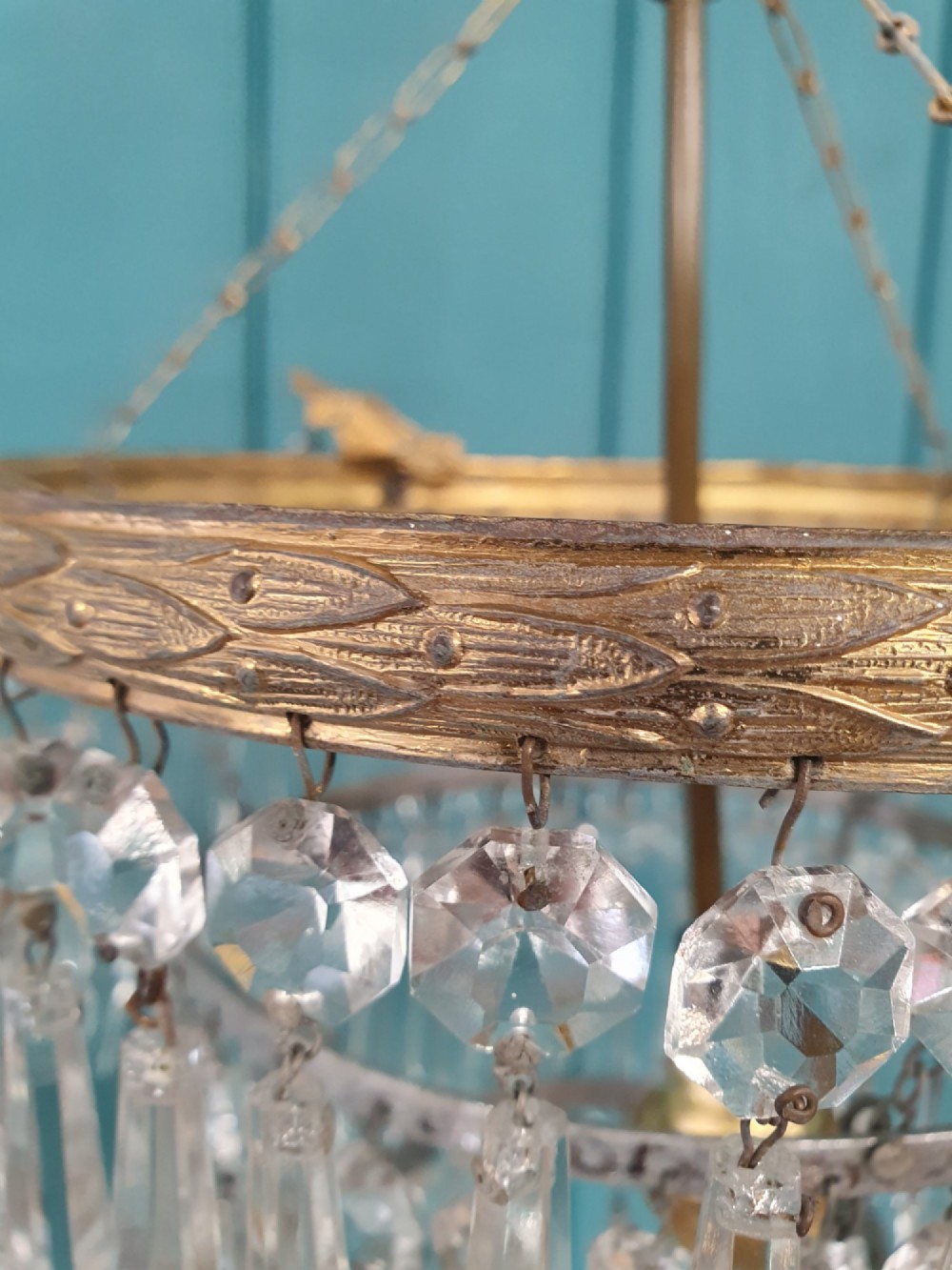 An antique three-tiered crystal chandelier featuring pointed prism spikes suspended from an ornate brass ring and central hanging chain. View III