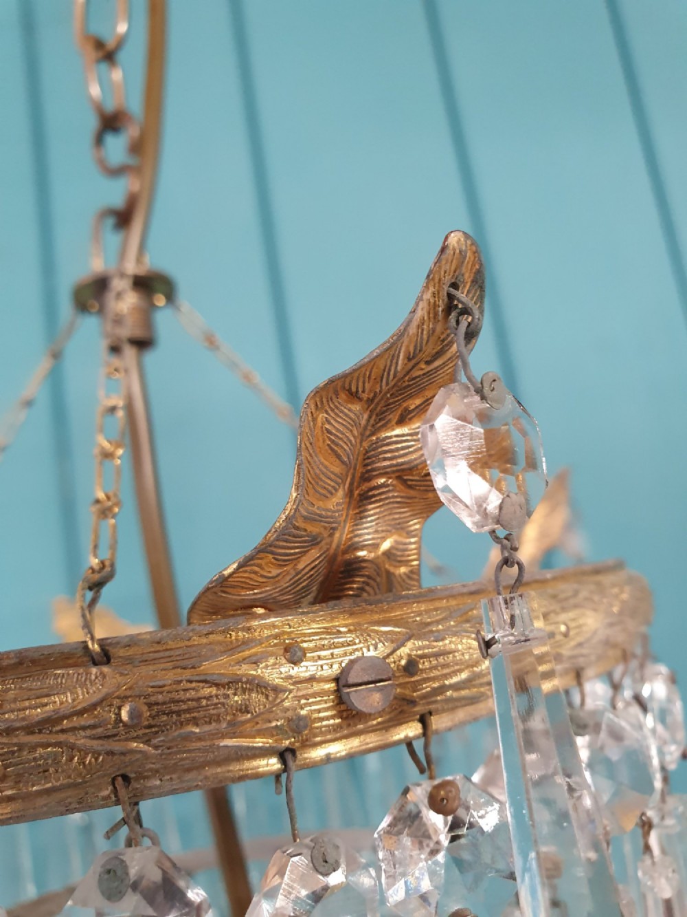 An antique three-tiered crystal chandelier featuring pointed prism spikes suspended from an ornate brass ring and central hanging chain. View IV