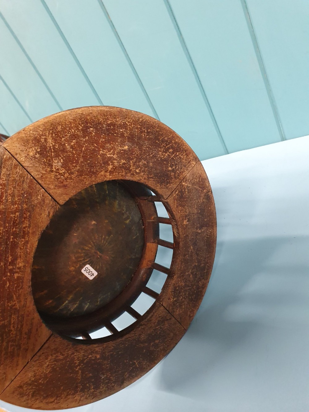 An early 20th-century oak stick stand featuring a flared, circular slatted framework tapering at the centre with an integrated metal drip tray at the circular base. View II