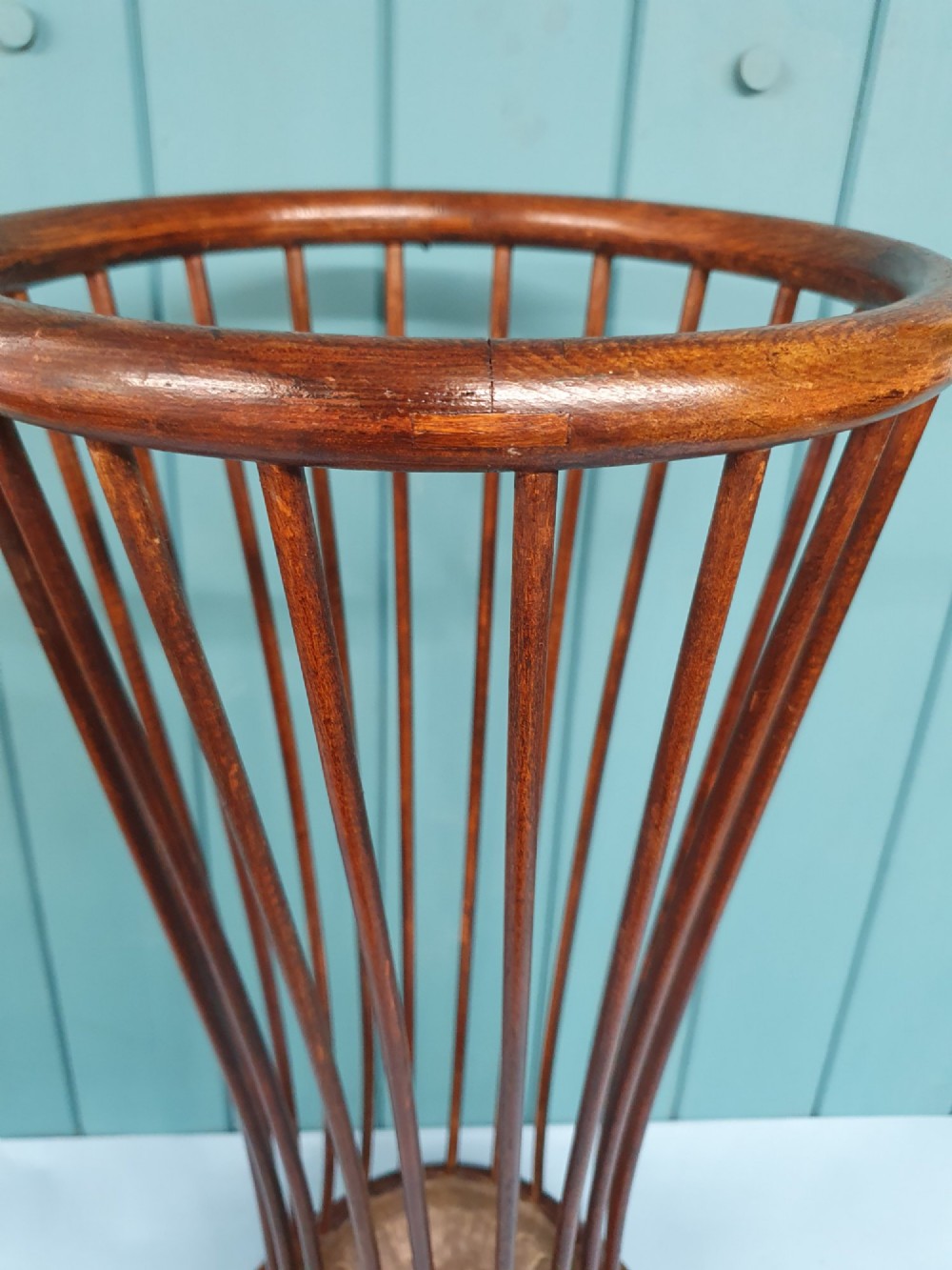 An early 20th-century oak stick stand featuring a flared, circular slatted framework tapering at the centre with an integrated metal drip tray at the circular base. View VI