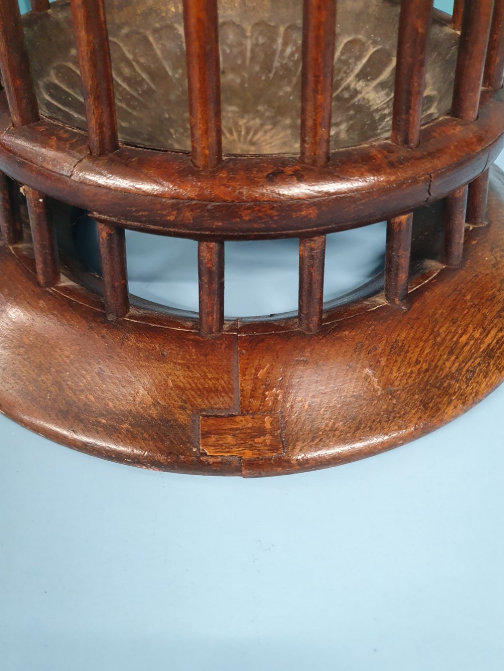 An early 20th-century oak stick stand featuring a flared, circular slatted framework tapering at the centre with an integrated metal drip tray at the circular base. View VII