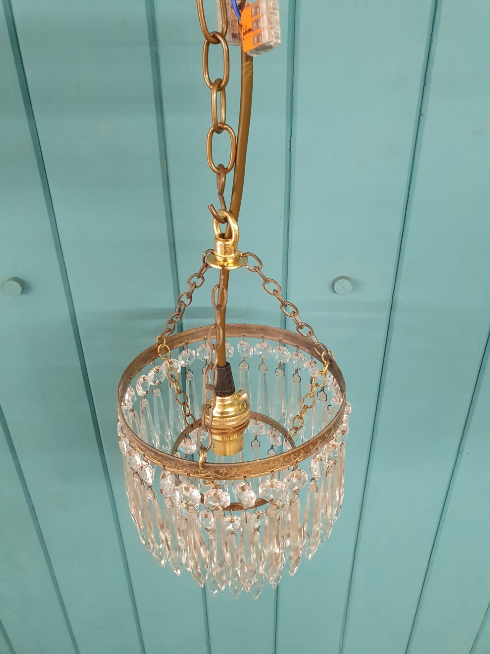 An early twentieth-century small brass ceiling light featuring suspended tiers of pointed cut glass crystal drops hanging from an ornate metal rim. View II