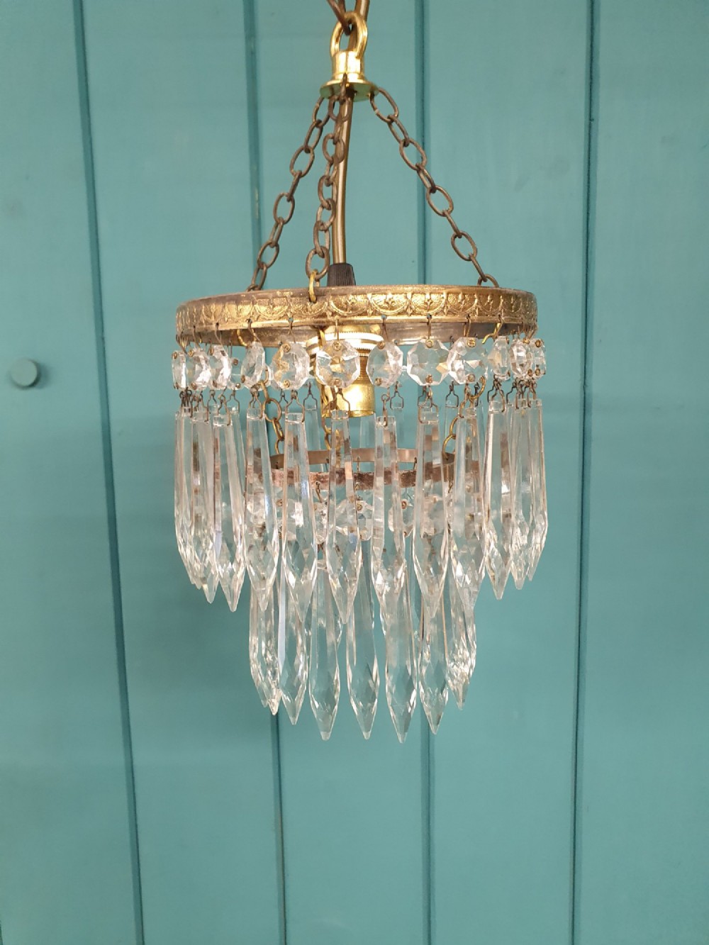 An early twentieth-century small brass ceiling light featuring suspended tiers of pointed cut glass crystal drops hanging from an ornate metal rim. View V