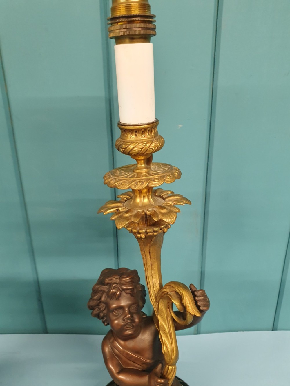 A pair of 1920s French-style dark bronze cherub table lamps with gilt foliate stems set on round black marble bases. View V