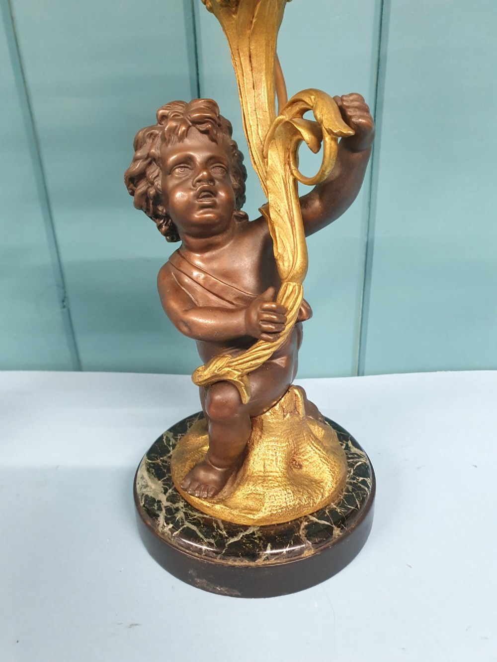 A pair of 1920s French-style dark bronze cherub table lamps with gilt foliate stems set on round black marble bases. View VII