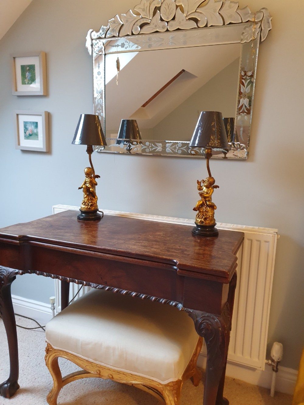 A pair of antique gilt brass table lamps featuring detailed sculpted cherub figures seated on circular dark marble bases. View III