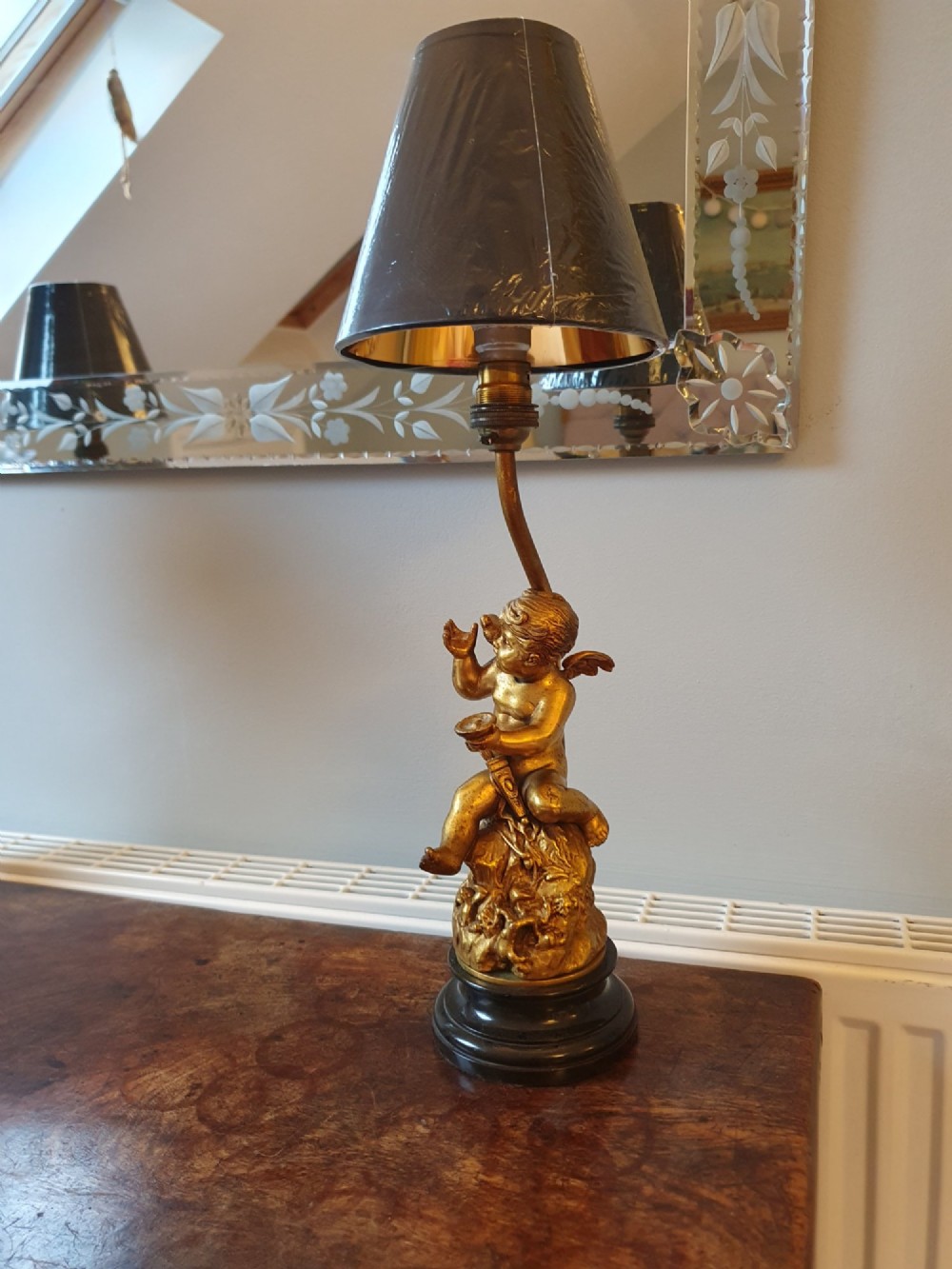 A pair of antique gilt brass table lamps featuring detailed sculpted cherub figures seated on circular dark marble bases. View IV