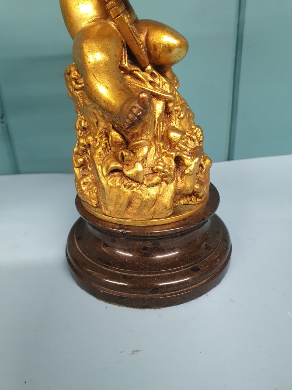 A pair of antique gilt brass table lamps featuring detailed sculpted cherub figures seated on circular dark marble bases. View VIII