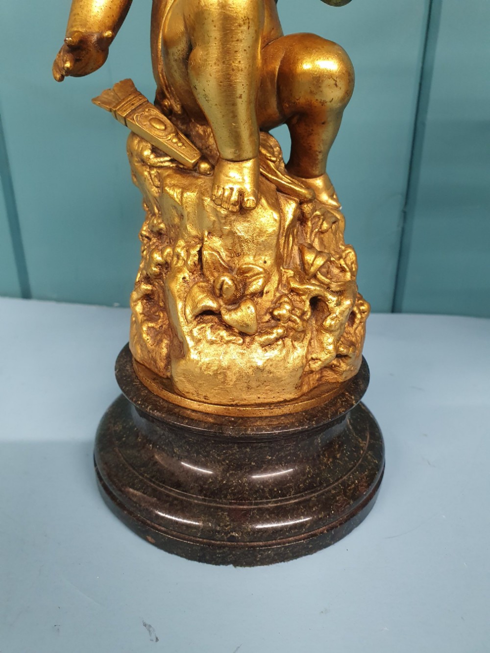 A pair of antique gilt brass table lamps featuring detailed sculpted cherub figures seated on circular dark marble bases. View XI