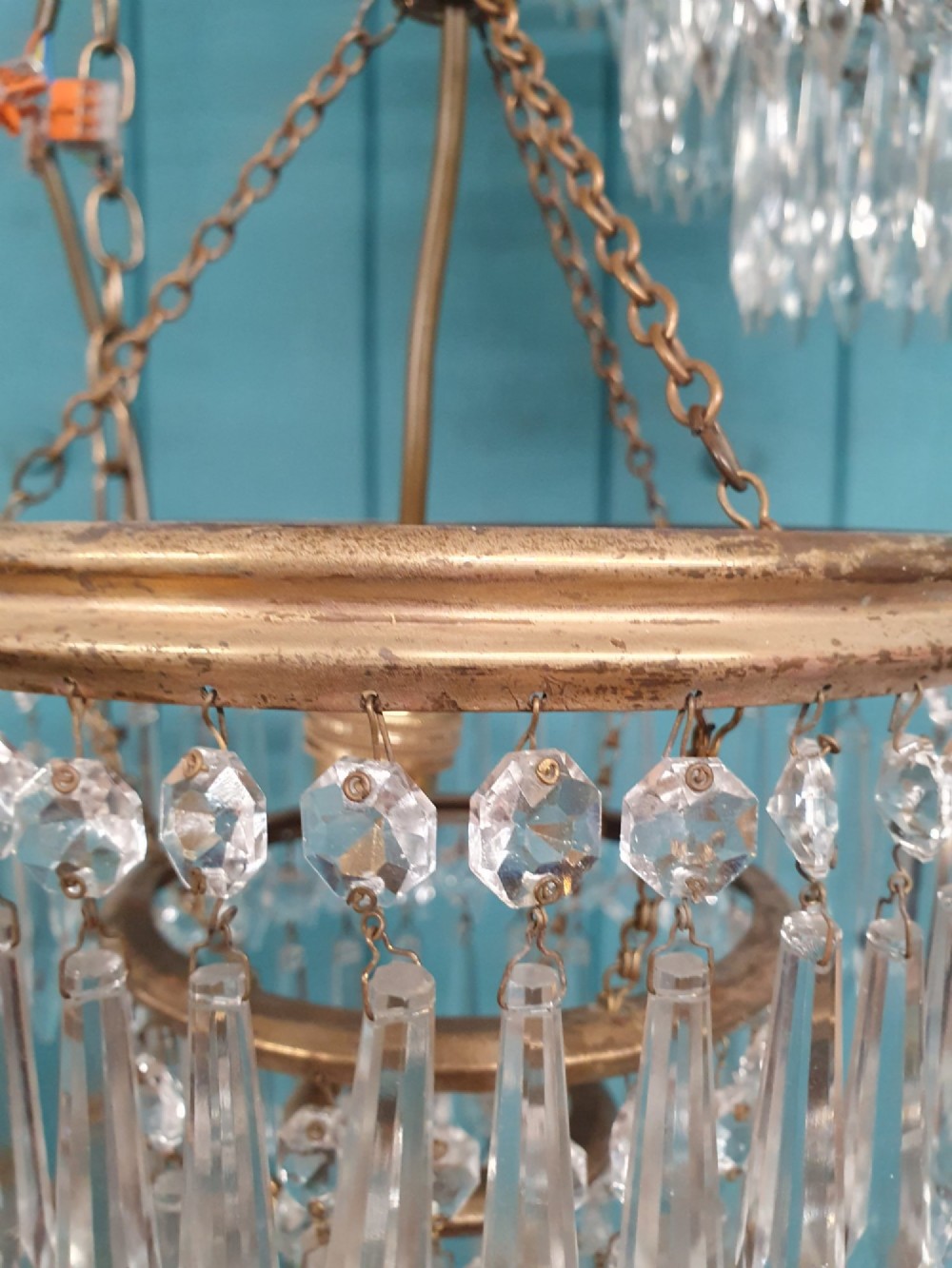 A set of three tiered brass pendant chandeliers featuring suspended clear crystal spike droplets. View IV