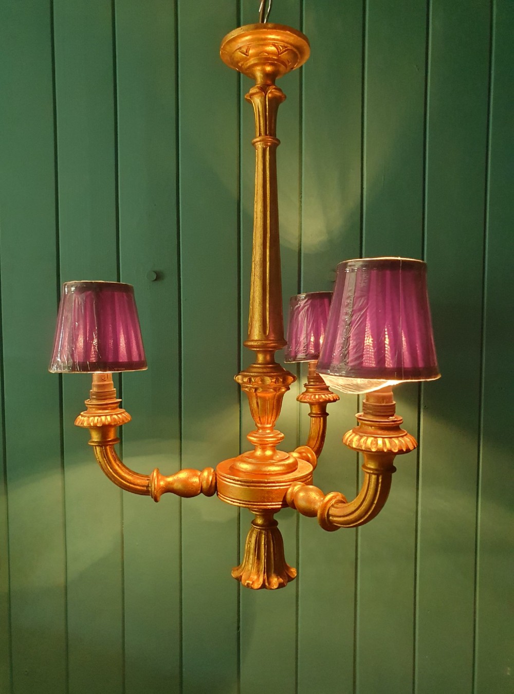 Circa 1900 carved giltwood three-arm chandelier featuring a central turned column, scrolled branches, fluted bottom drop, and three purple fabric lampshades. View II