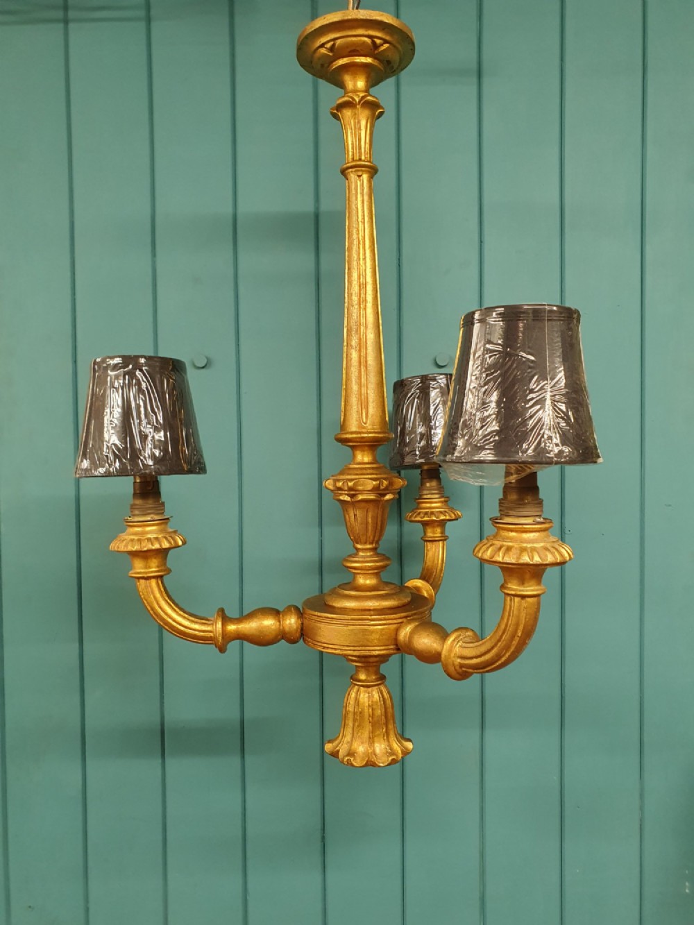 Circa 1900 carved giltwood three-arm chandelier featuring a central turned column, scrolled branches, fluted bottom drop, and three purple fabric lampshades. View IV