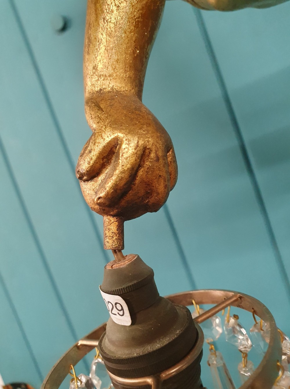 An antique gilt spelter flying winged cherub suspended from a chain, holding two light sockets decorated with cut glass crystal drops. View II