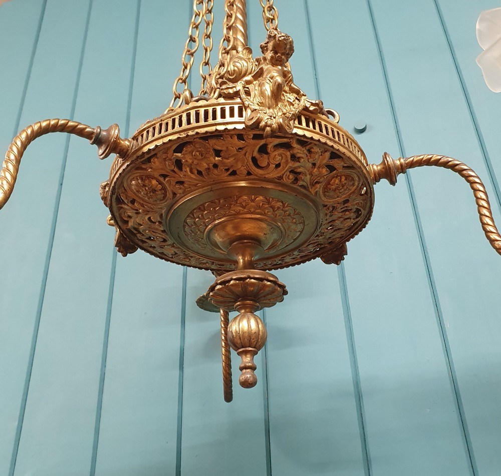 A French ebonised and brass three-arm chandelier featuring twisted metal arms, supporting chain suspension, and frosted glass shades shaped like open flowers. View III