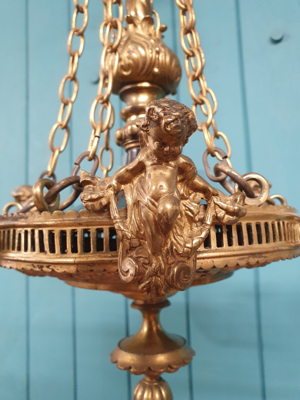 A French ebonised and brass three-arm chandelier featuring twisted metal arms, supporting chain suspension, and frosted glass shades shaped like open flowers. View IV