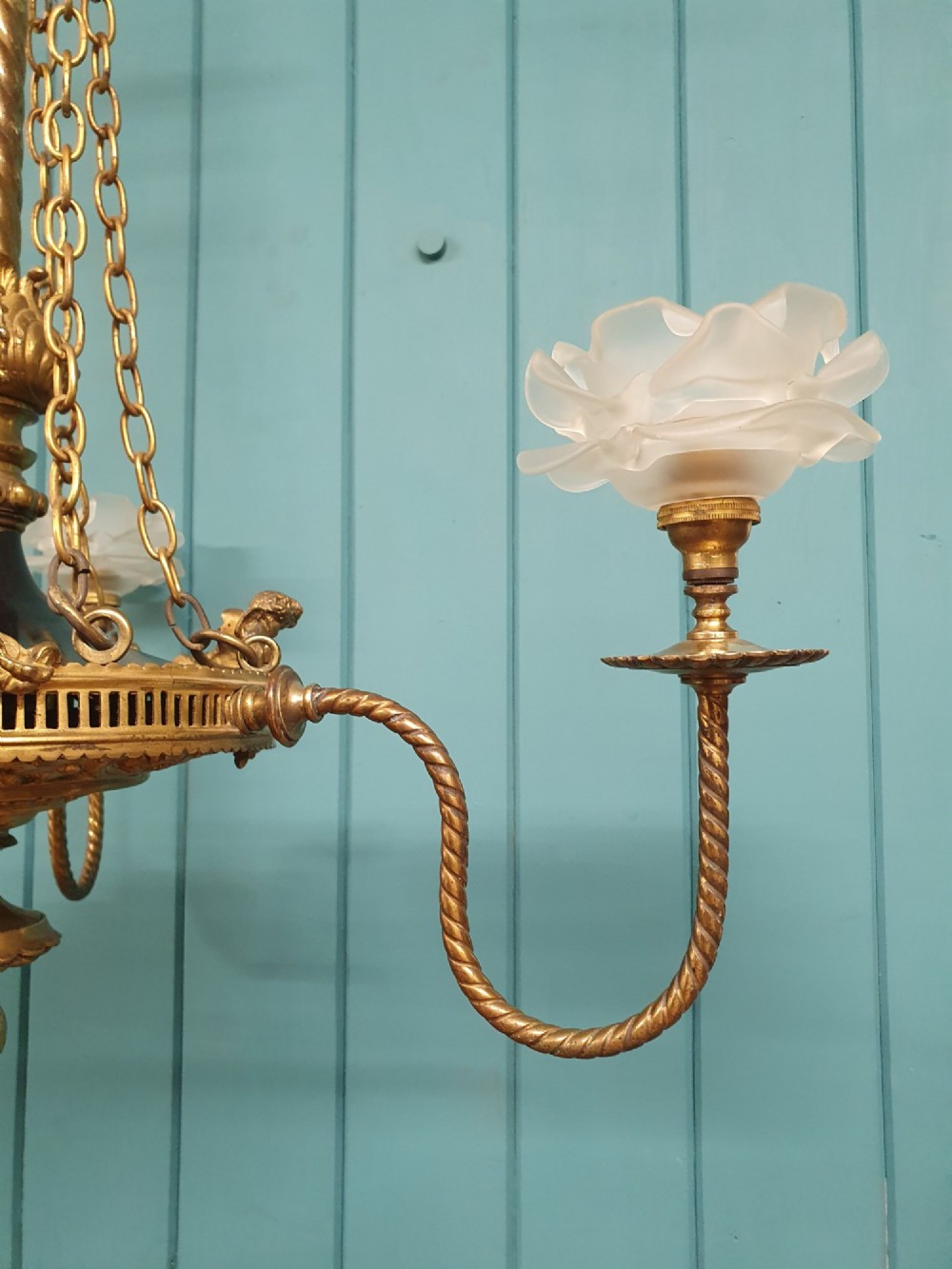 A French ebonised and brass three-arm chandelier featuring twisted metal arms, supporting chain suspension, and frosted glass shades shaped like open flowers. View VII