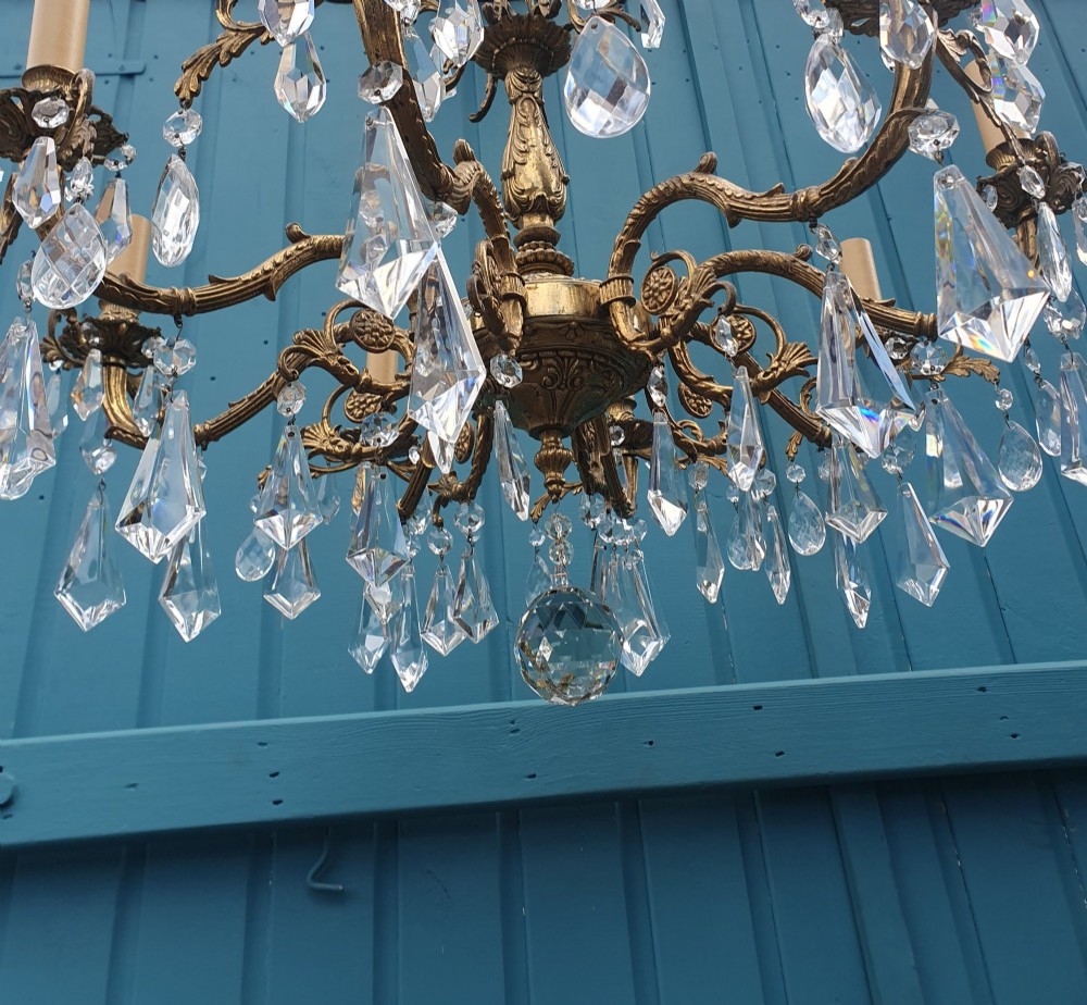 An eight-arm French gilt brass chandelier decorated with scrolling foliate detail, faux candle sleeves, and faceted hanging cut-glass crystal drops. View II