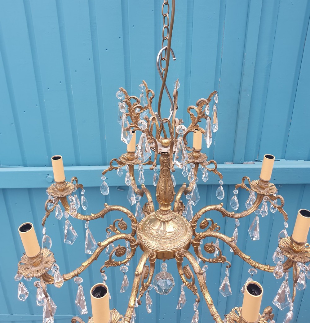 An eight-arm French gilt brass chandelier decorated with scrolling foliate detail, faux candle sleeves, and faceted hanging cut-glass crystal drops. View III