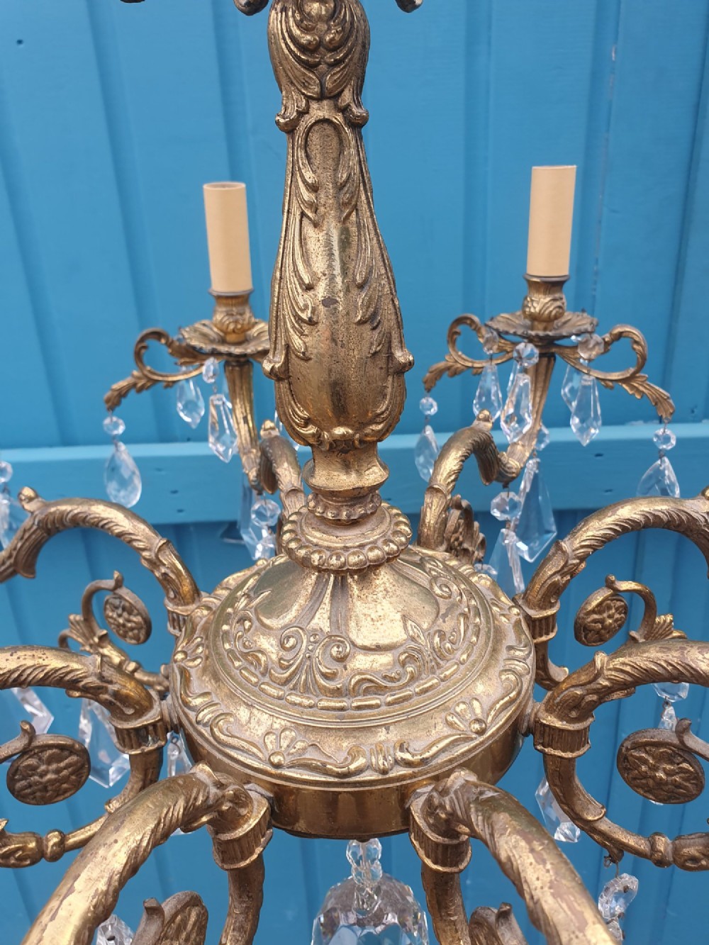 An eight-arm French gilt brass chandelier decorated with scrolling foliate detail, faux candle sleeves, and faceted hanging cut-glass crystal drops. View IV