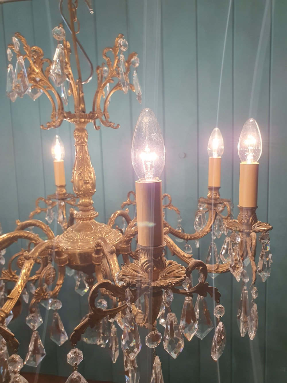 An eight-arm French gilt brass chandelier decorated with scrolling foliate detail, faux candle sleeves, and faceted hanging cut-glass crystal drops. View VII