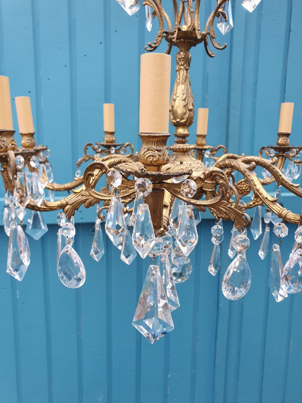 An eight-arm French gilt brass chandelier decorated with scrolling foliate detail, faux candle sleeves, and faceted hanging cut-glass crystal drops. View VIII