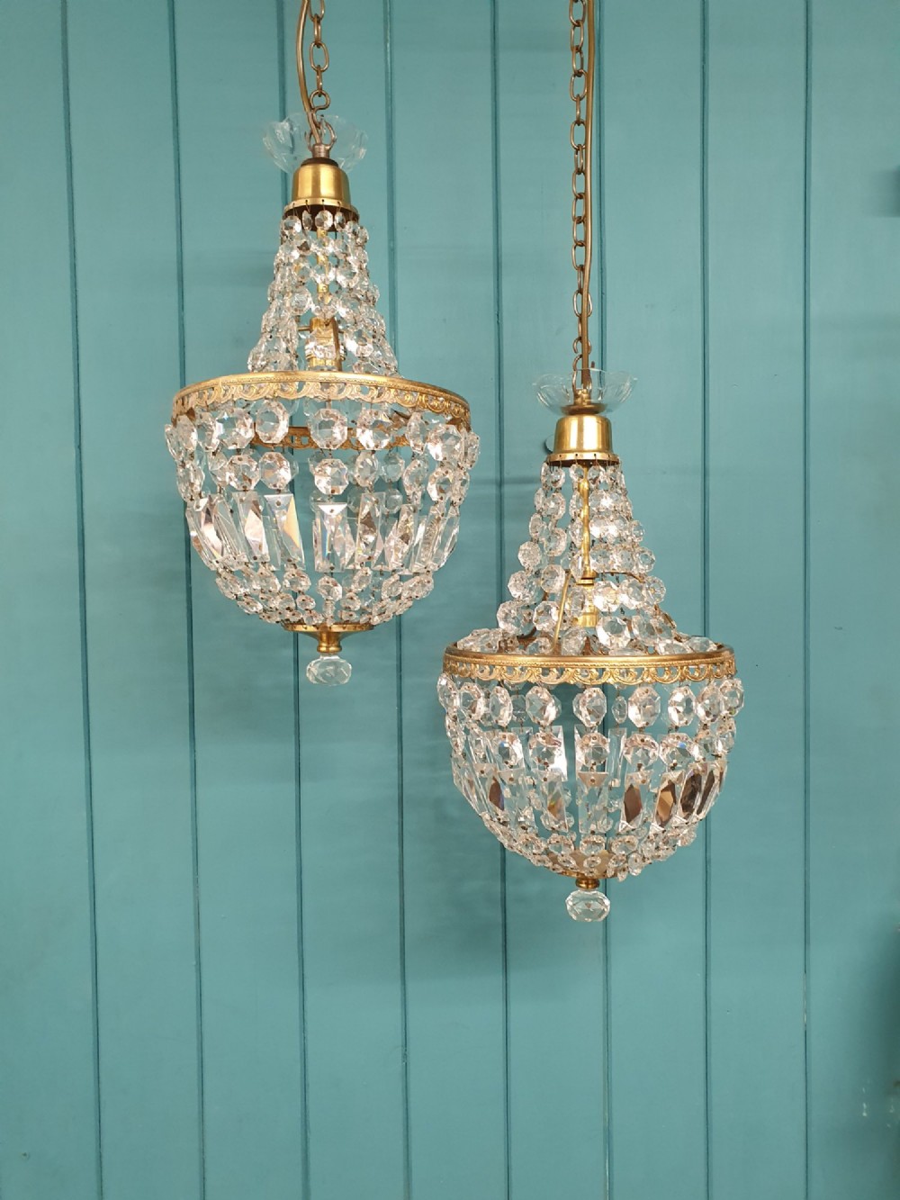A pair of early 20th-century tent-style chandeliers featuring tier upon tier of faceted cut glass crystal beads and brass fittings.