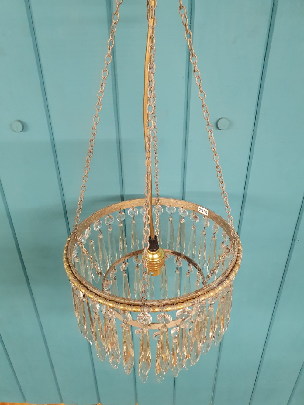 A small early 20th-century pendant chandelier featuring tiered cut-glass crystal spikes suspended from a brass circular frame and hanging chain. View II