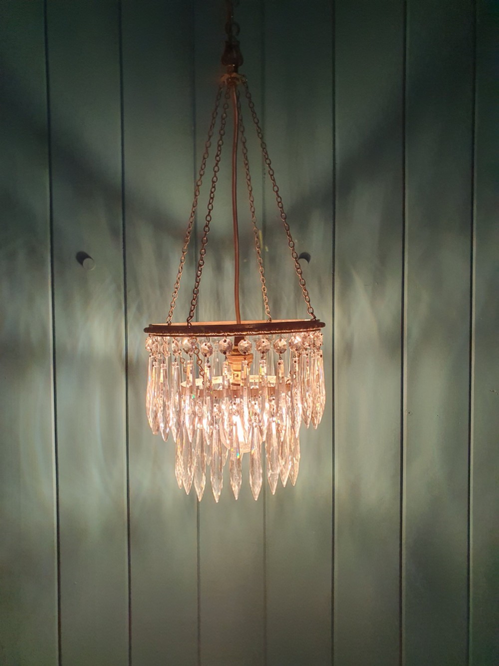 A small early 20th-century pendant chandelier featuring tiered cut-glass crystal spikes suspended from a brass circular frame and hanging chain. View III