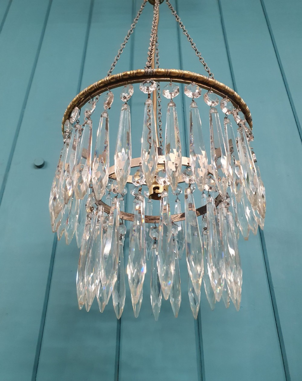 A small early 20th-century pendant chandelier featuring tiered cut-glass crystal spikes suspended from a brass circular frame and hanging chain. View IV