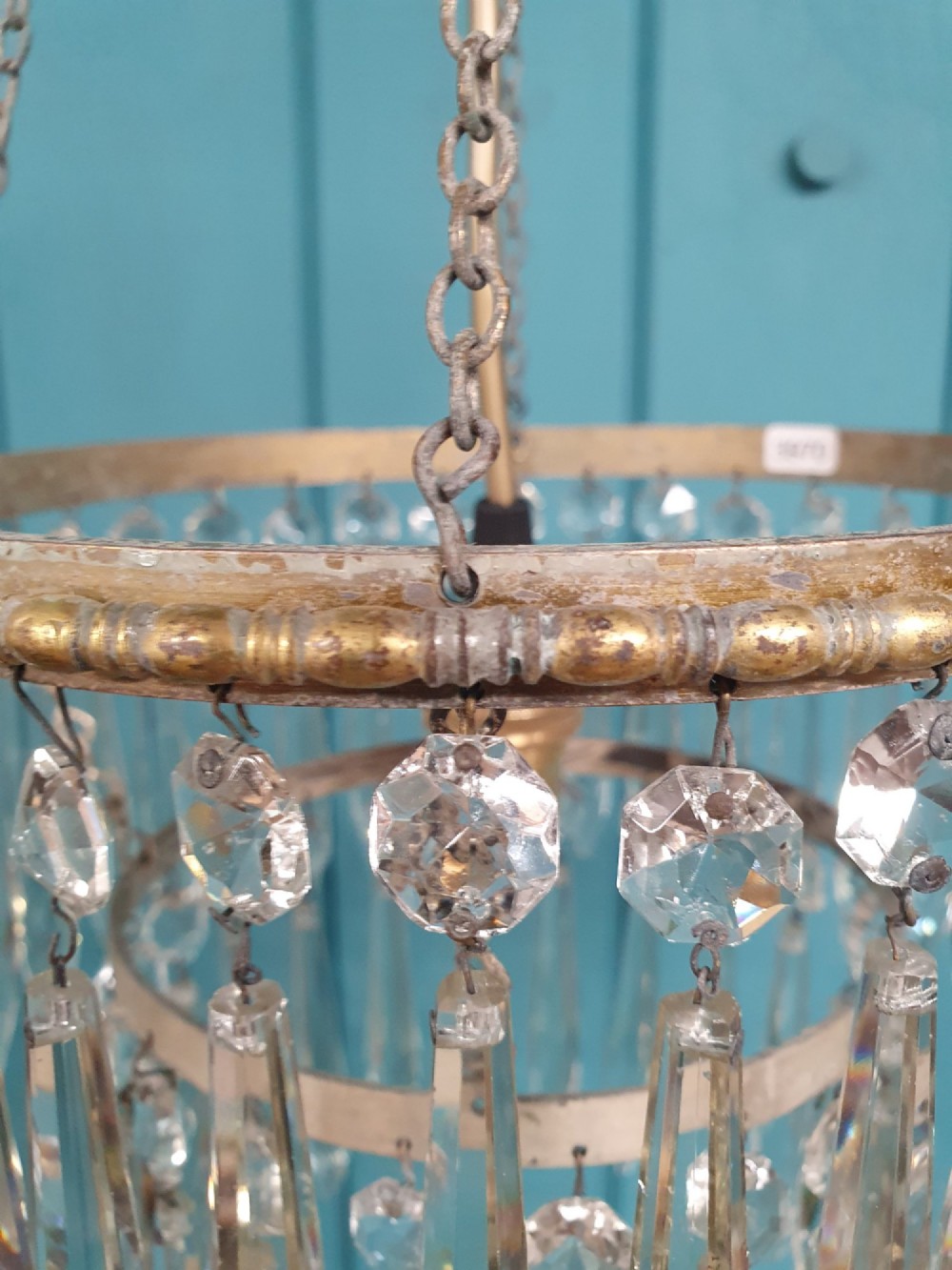 A small early 20th-century pendant chandelier featuring tiered cut-glass crystal spikes suspended from a brass circular frame and hanging chain. View V