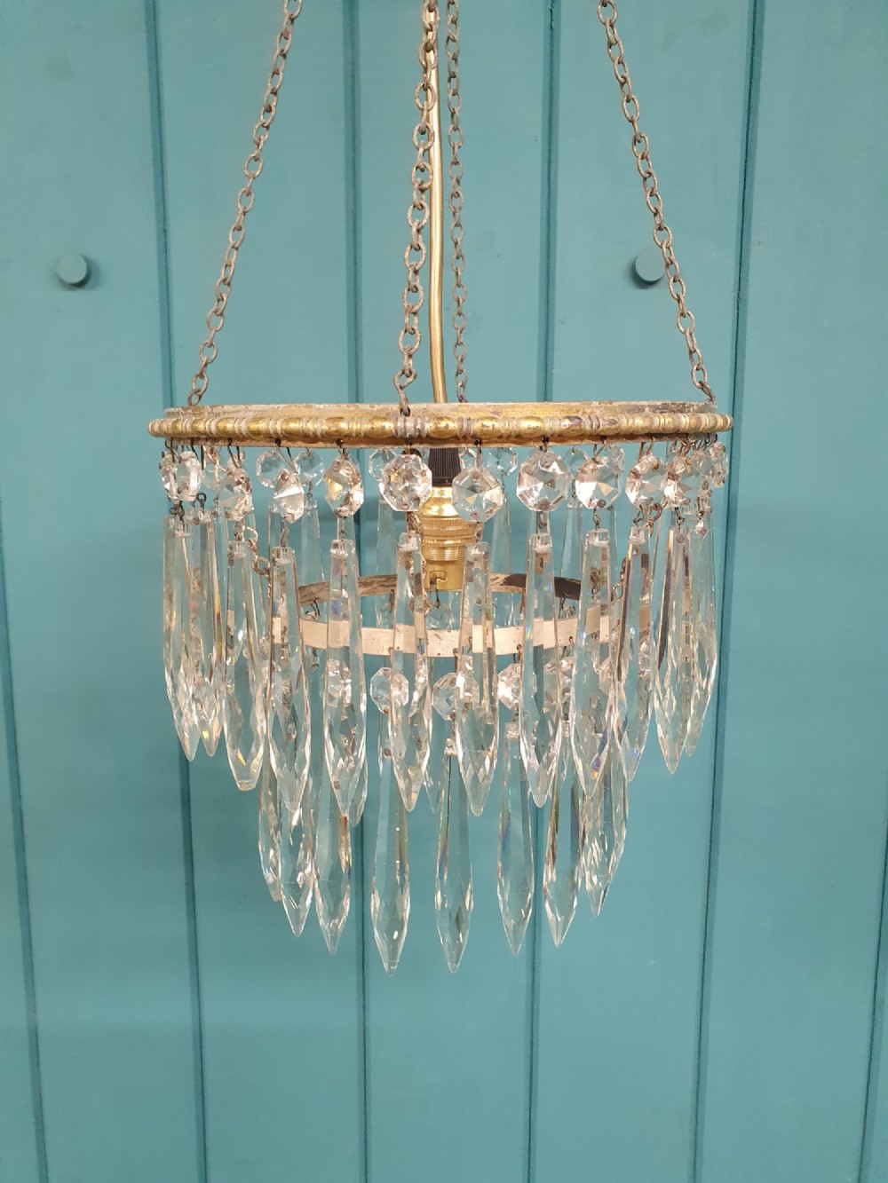A small early 20th-century pendant chandelier featuring tiered cut-glass crystal spikes suspended from a brass circular frame and hanging chain. View VI