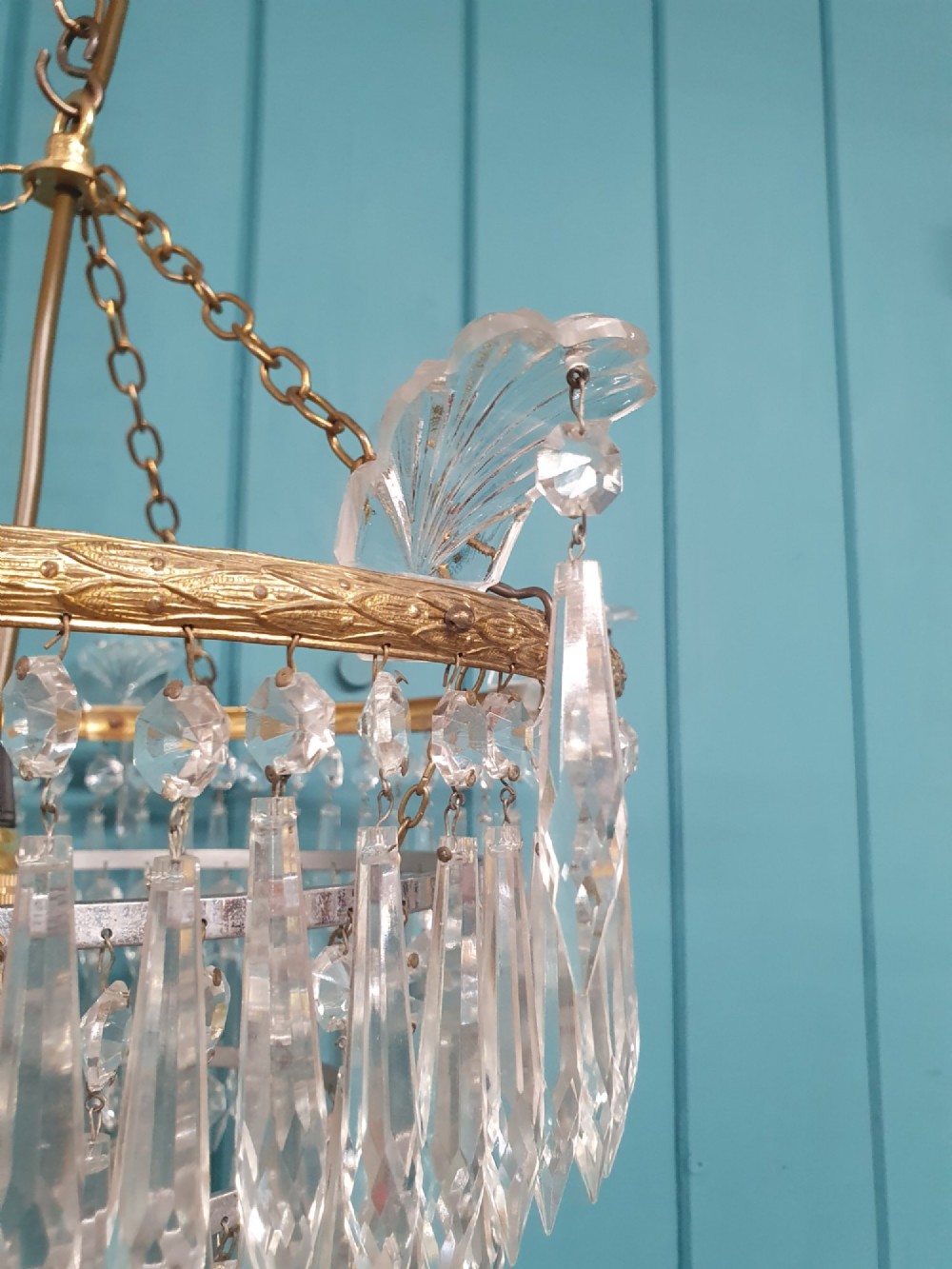 An early twentieth-century four-tiered chandelier featuring hanging glass crystal spikes suspended from a decorated brass rim with chain hanging apparatus. View III