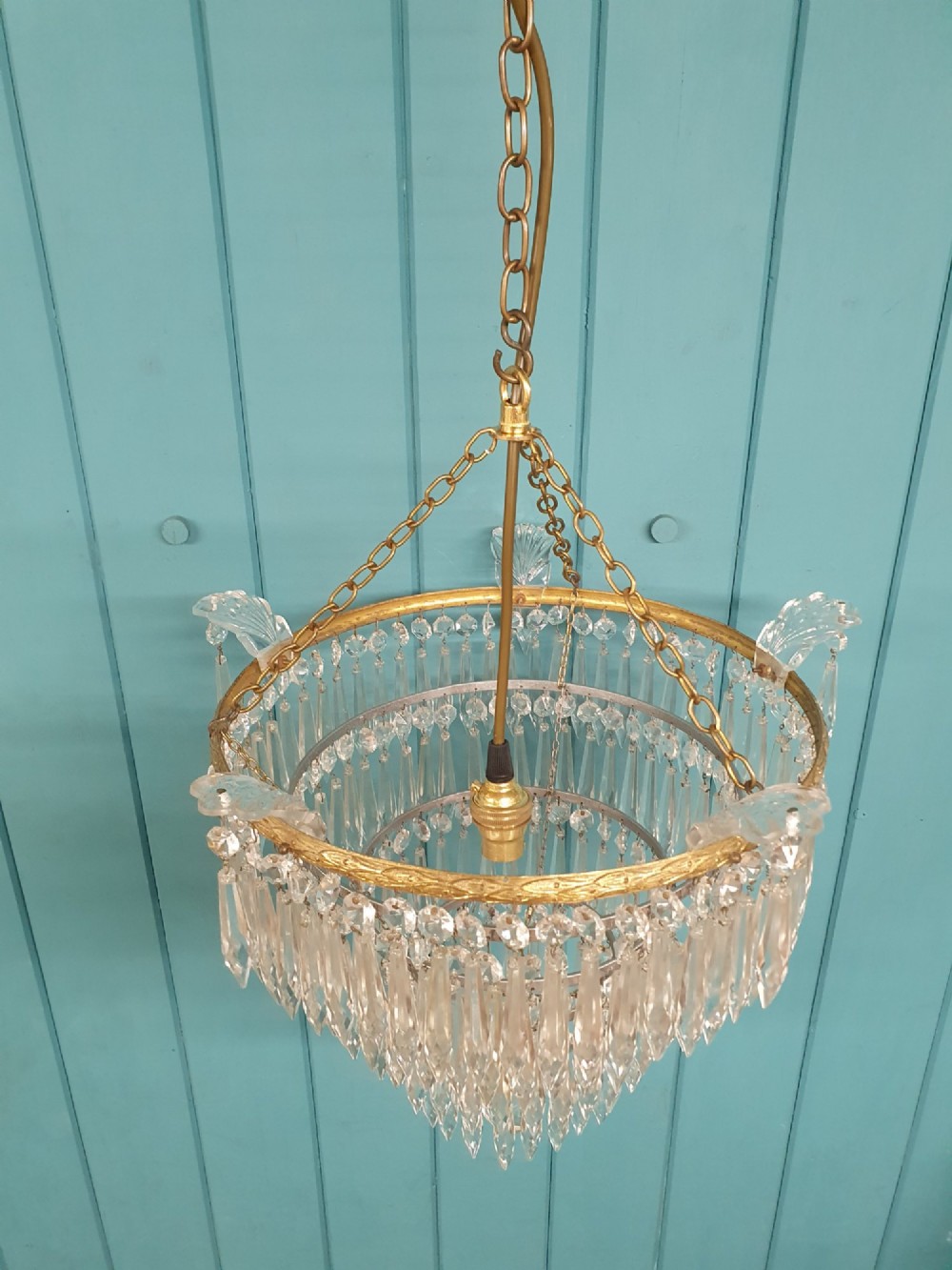 An early twentieth-century four-tiered chandelier featuring hanging glass crystal spikes suspended from a decorated brass rim with chain hanging apparatus. View V
