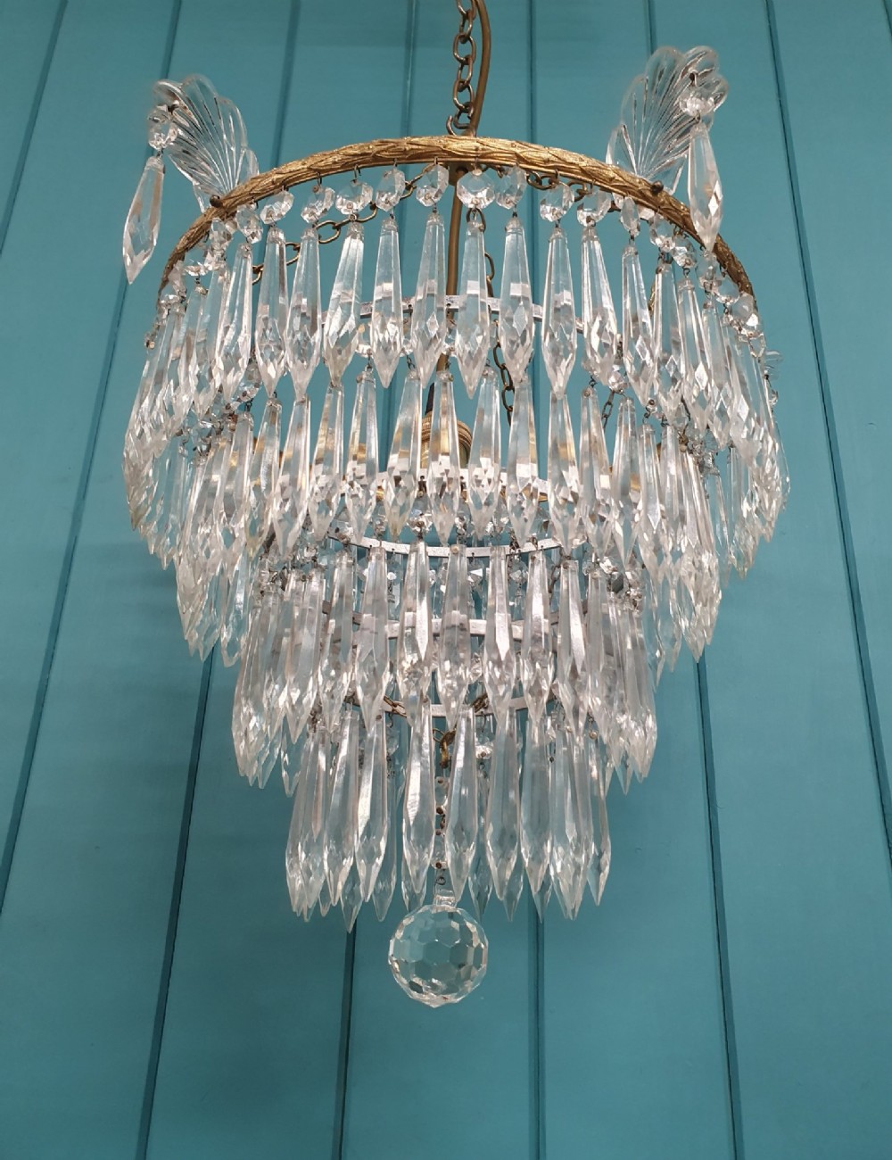 An early twentieth-century four-tiered chandelier featuring hanging glass crystal spikes suspended from a decorated brass rim with chain hanging apparatus. View VI