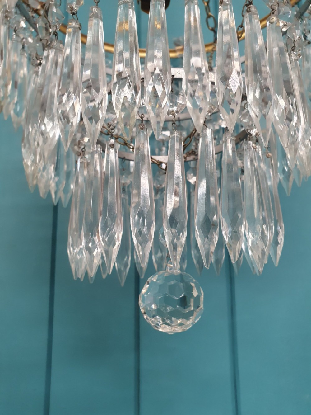 An early twentieth-century four-tiered chandelier featuring hanging glass crystal spikes suspended from a decorated brass rim with chain hanging apparatus. View VII