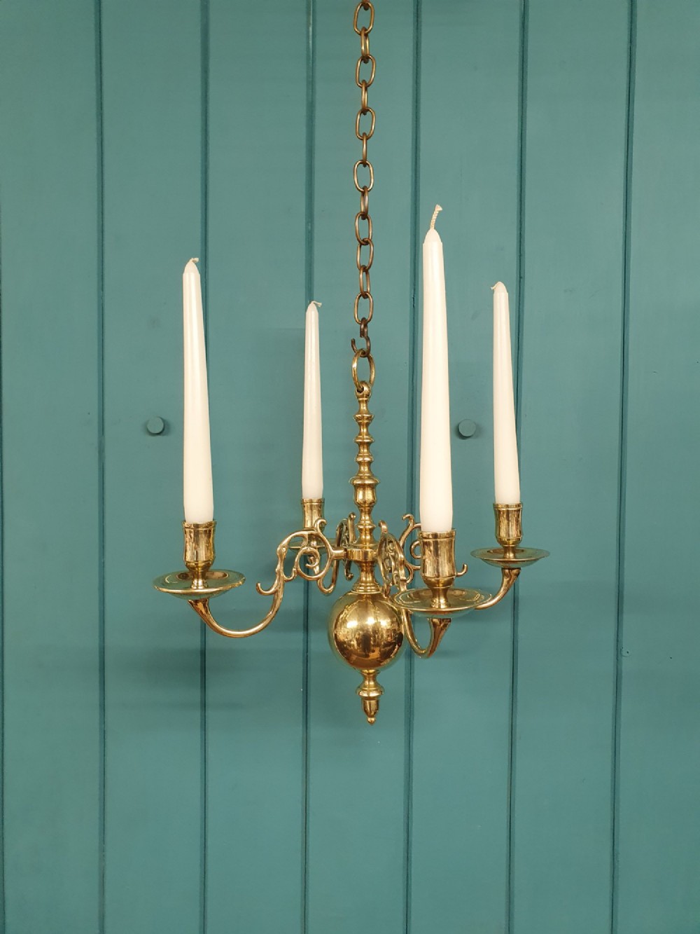 A small four-arm brass candle chandelier featuring scroll branches and a central turned column suspended from a brass chain. View III