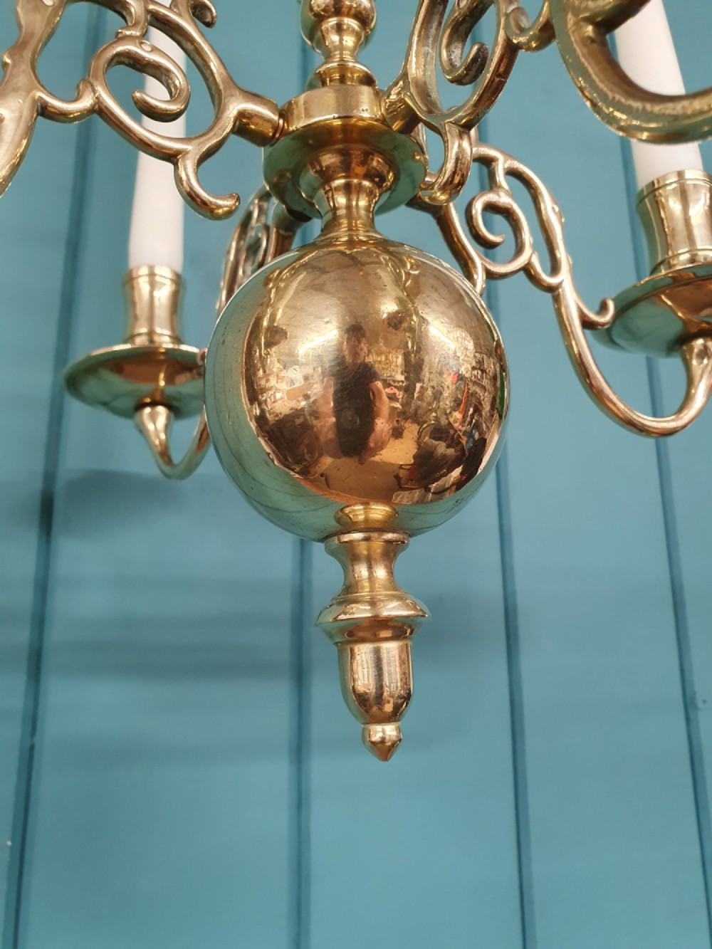 A small four-arm brass candle chandelier featuring scroll branches and a central turned column suspended from a brass chain. View V
