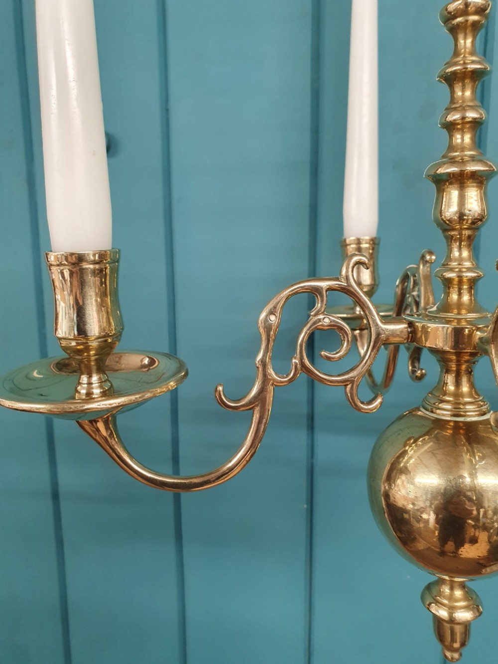 A small four-arm brass candle chandelier featuring scroll branches and a central turned column suspended from a brass chain. View VI