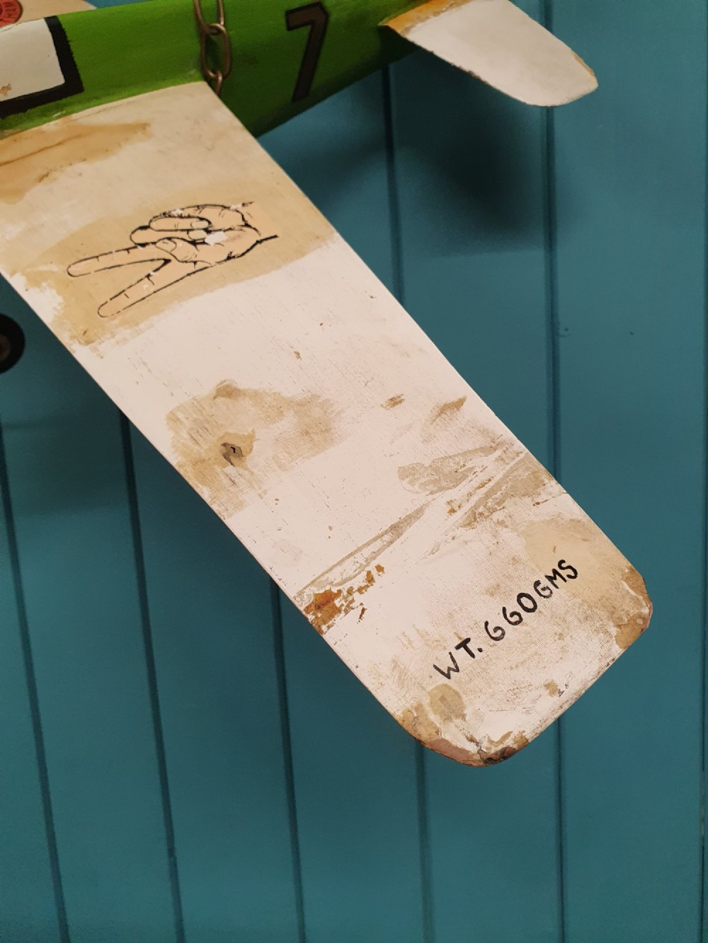A mid-century hand-painted balsa wood control-line model aeroplane finished in green and cream with number seven painted on the fuselage. View II