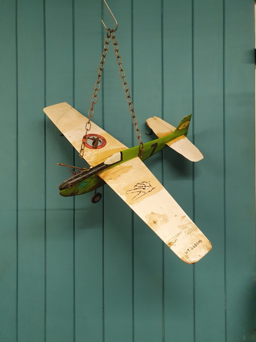 A mid-century hand-painted balsa wood control-line model aeroplane finished in green and cream with number seven painted on the fuselage.