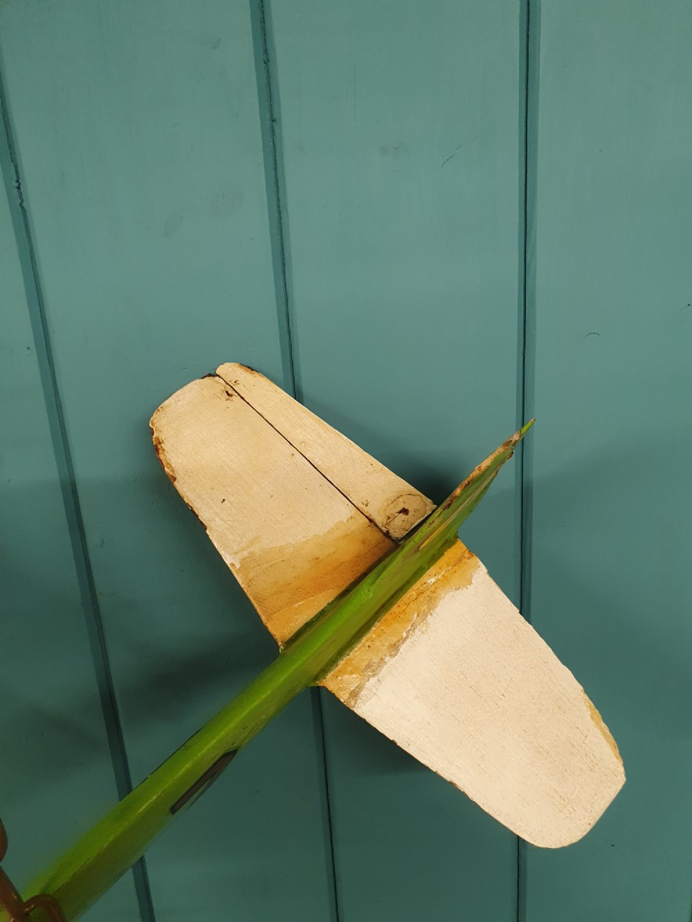 A mid-century hand-painted balsa wood control-line model aeroplane finished in green and cream with number seven painted on the fuselage. View IV