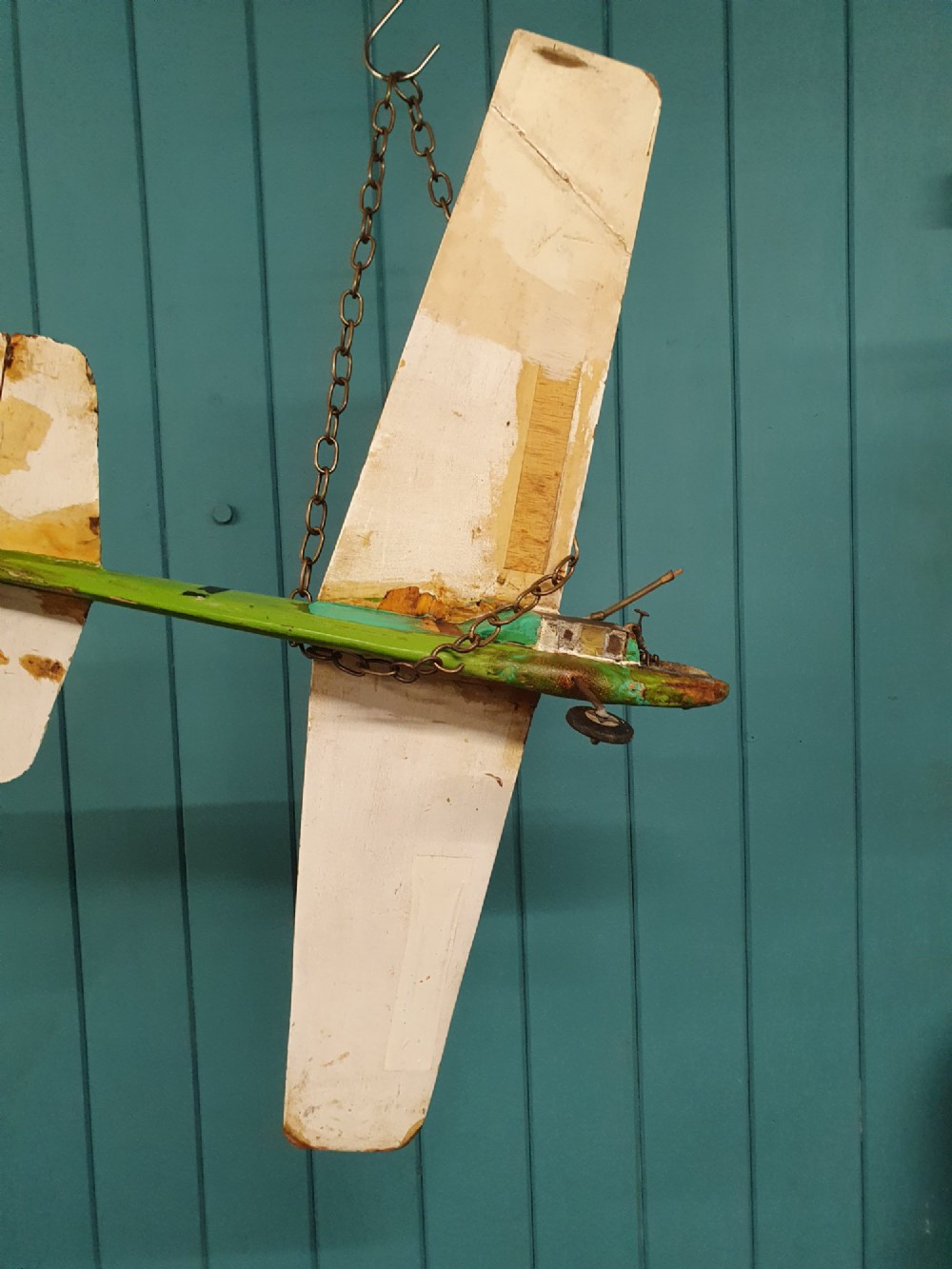 A mid-century hand-painted balsa wood control-line model aeroplane finished in green and cream with number seven painted on the fuselage. View VI