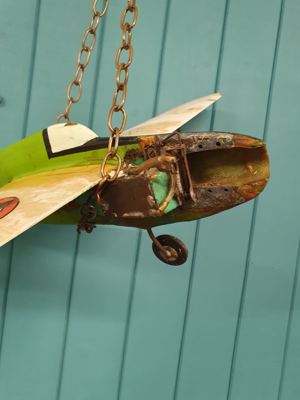 A mid-century hand-painted balsa wood control-line model aeroplane finished in green and cream with number seven painted on the fuselage. View VII