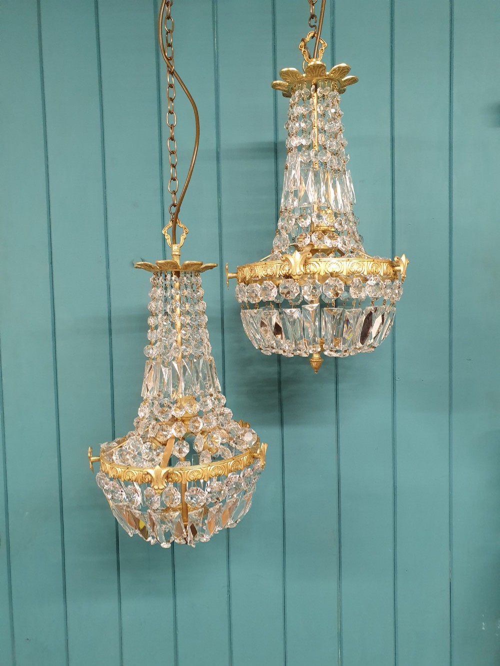 A pair of early 20th-century cut glass and brass tent chandeliers featuring tapered crystal bead strands and a lower band of rectangular faceted prisms.